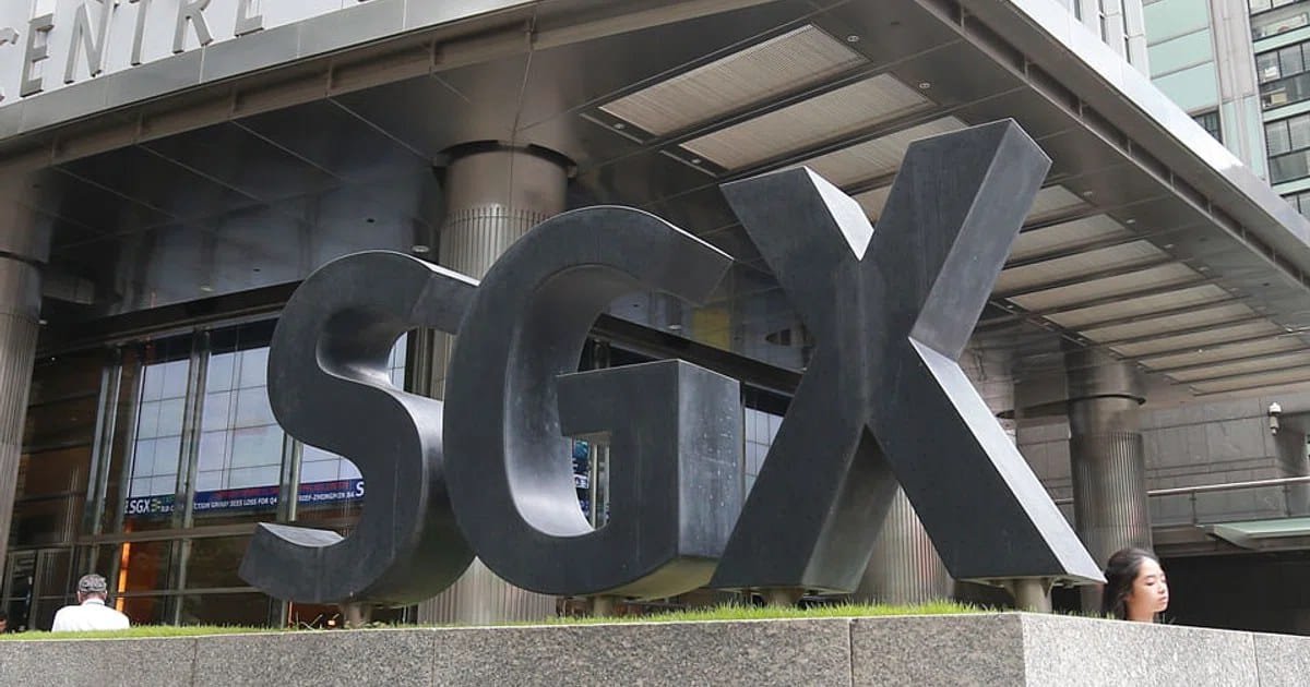 Large black SGX letters forming a sign outside the Singapore Exchange building, with people walking nearby and the building's glass facade visible in the background